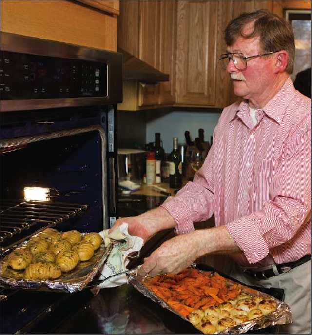 Photo by Katharine Schroeder | Chef John Ross places the potatoes, carrots and onions in the oven to roast.