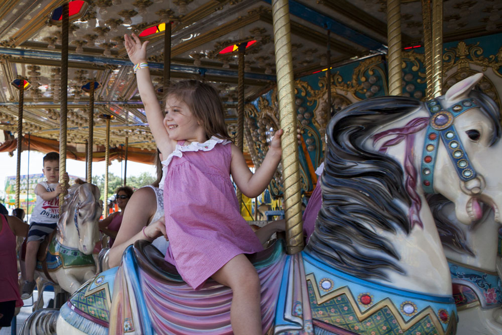 A little girl waves from the carousel. (Credit: Katharine Schroeder)