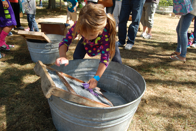 Cora D'Alsace launders a piece of cloth on an old-fashioned washing board.