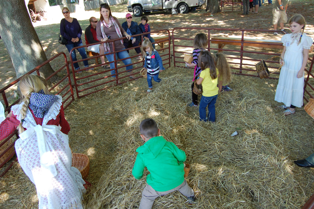 Kids hunt for items in some hay.