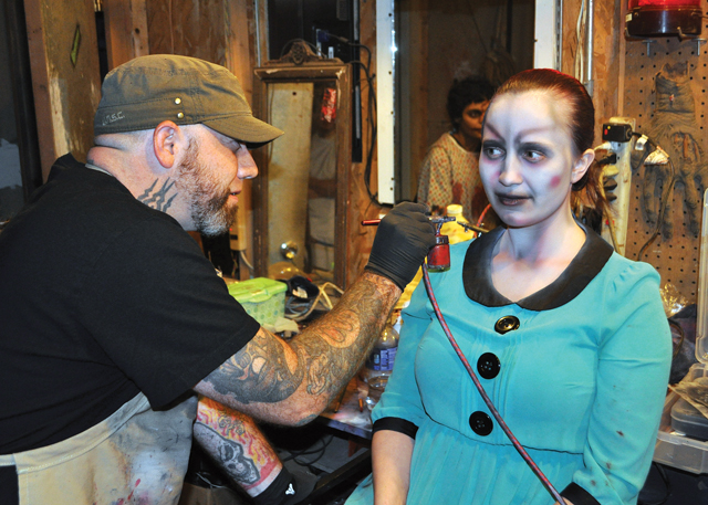 Ms. Young's face and neck are painted in ghoulish shades of blue and white and then topped with black lips and red gashes.