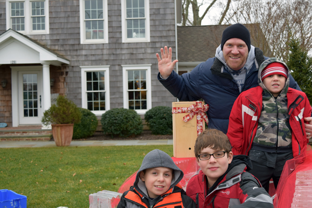 Paul Helbig of Manorville and his boys Ryan, 6, (top) Justin, 9, (bottom left) and Sean, 12, (bottom right) pose for a photo on Santa's sleigh.