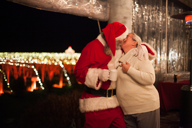 Santa gives his Mrs. Claus a kiss.