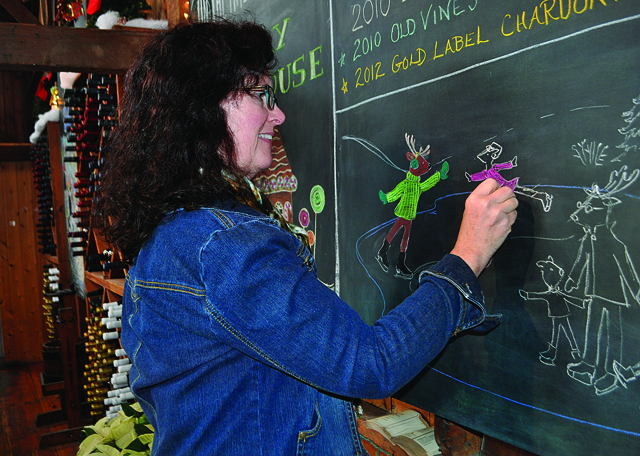 Pat Olstad of Cutchogue uses pastel chalk to draw a family of reindeer on skates at The Lenz Winery in Peconic last week. (Credit: Rachel Young)