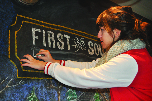 RACHEL YOUNG PHOTO Kara Hoblin of Greenport adds text to a chalkboard display at First and South restaurant in Greenport last week. (Credit: Rachel Young)