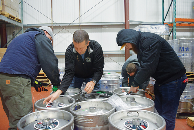 Greenport Harbor Brewing Co. chef Brian Russell, co-owner Rich Vandenburgh and brewer's assistant Asa Davis prepare kegs of Flat Iron Ale, a colloboration between GHB and 212 Brewing. Co., for distribution. (Credit: Vera Chinese)