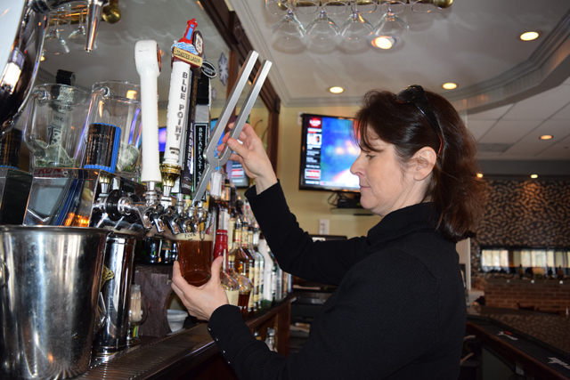 Sandra Bilotti, manager at CJ's American Grill in Mattituck, pulls the tuning fork shaped tap handle to pour a pint of Chromatic pale ale. (Credit: Vera Chinese)