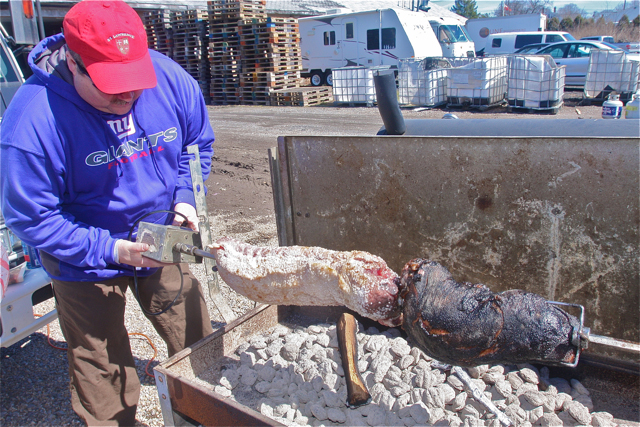 Greg Meyers of Wading River lowers pork and roast beef on to the barbecue coals.