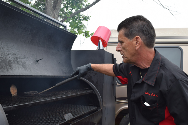 John Forgione of Rolling Grill Barbecue cleans off the grill.