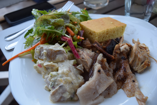 A plate of pig, blue cheese potato salad, KK's greens and corn bread.