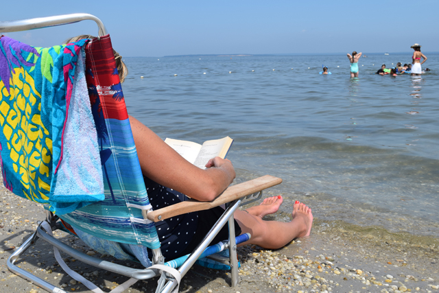 Lauren Wallace of Riverhead enjoys a book as her son Zachary Gevinski, 6, plays in the water.