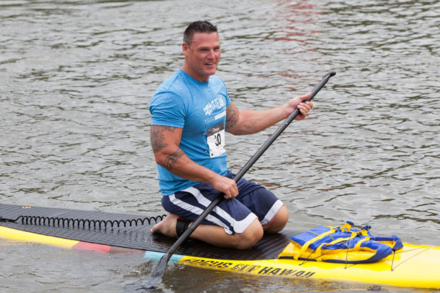 A contestant kneels on his board after completing a stand up paddle run.