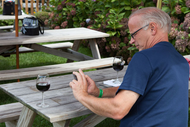Bruce Marx of St. James takes a photo of his wine to send to a friend who couldn't attend the event.