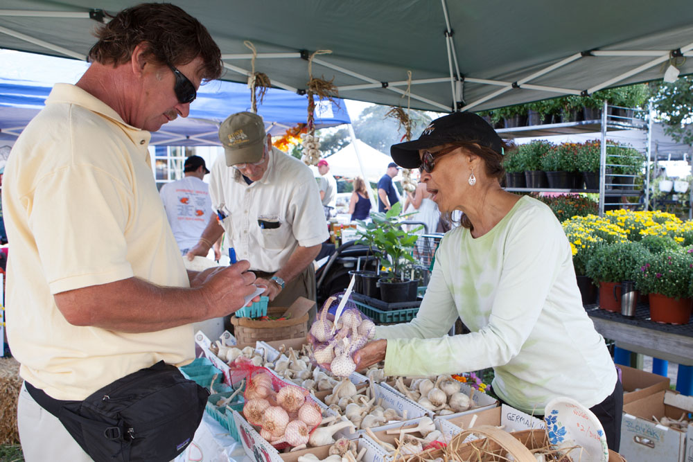 Elizabeth Dickenson of Biophilia Organic Farm in Jamesport serves Bob Markowski of Massapequa. In the backgroud is farmer Phil Barbado.