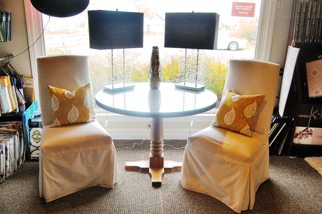 Neutral-color chairs with gold throw pillows flank a wood-and-glass table at Wallace Home Design. (Credit: Rachel Young)