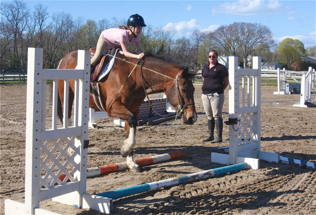 Hedgewood Farm owner and instructor Dawn Hommel (right) teaches Giavonna Scharf, 9, of Southold, to jump over a cavaletti.