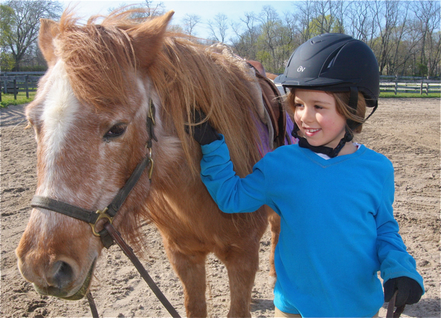 Elle O'Neill, 7, of Peconic, poses with pony Pebbles after her lesson.