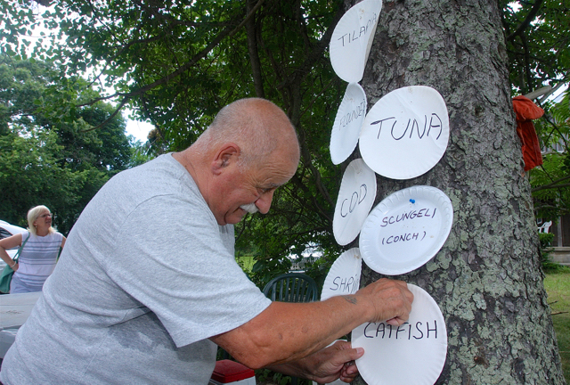 Bob’s friend Joe Cavaluzzi of Flanders pins up the paper plate signs on a tree next to the stand. (Credit: Barbaraellen Koch)