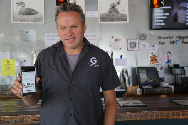 Greenport Harbor Brewing Co. co-owner John Liegey shows off the app on his phone. (Credit: Krysten Massa)