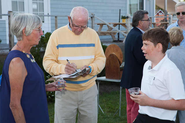 Volunteer Will Sullivan, right, sells a raffle ticket to his grandfather Jeff Sufflivan as Suzie Fox looks on.