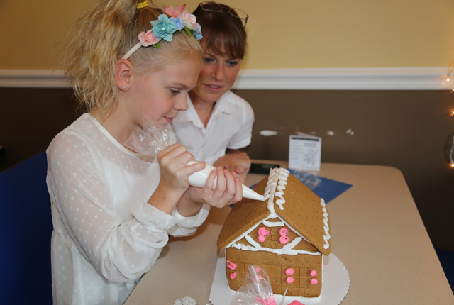 10-year old Carley Lamond of Wading River decorates her gingerbread house as mom, Maryann Lamond looks on.