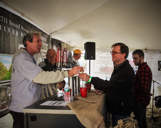 Bill King of Riverhead Ciderhouse (left) hands cider to George Macy (right) of Holtsville. Bill King is the brother of Riverhead Ciderhouse owner John King.